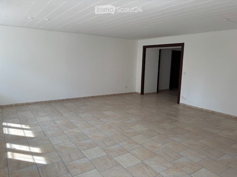 Empty room with white walls, tiled floor, and two doors leading to other rooms.