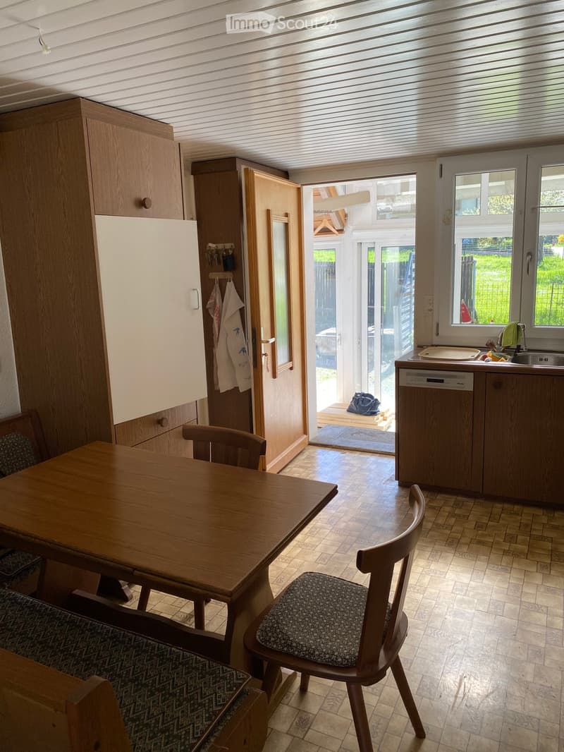 kitchen with dining area, wooden table, chairs, dishwasher, wooden cabinets, open door to outside