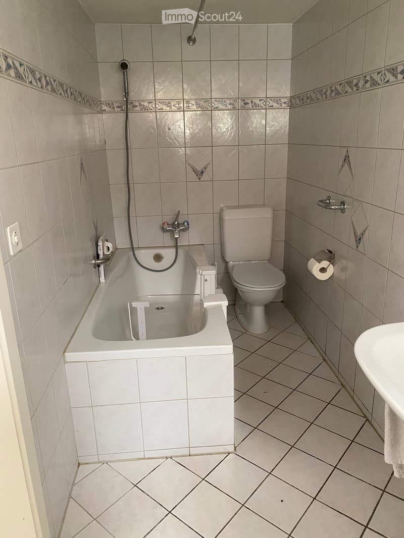 Bathroom with bathtub, toilet, sink, and white tiles