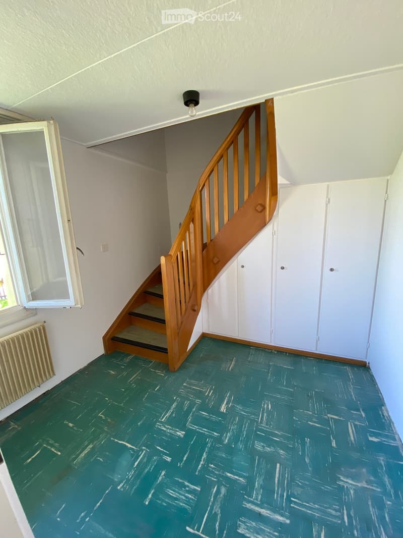 Empty room with wooden staircase, white walls, green floor, white doors, window with white frame
