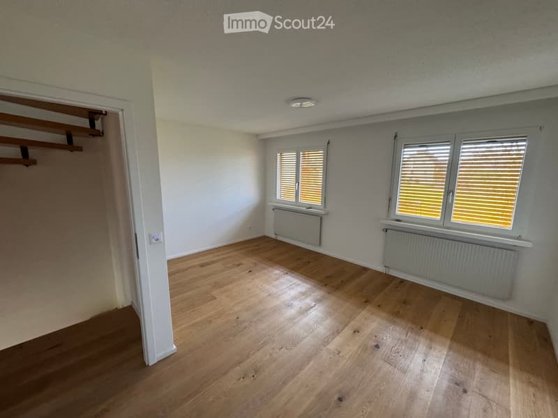 empty room, wooden floor, white walls, two windows with shutters, radiators