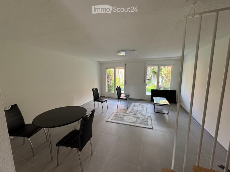 modern room with white walls, gray floor, black table and chairs, glass doors, and a coffee table