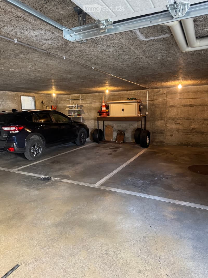 underground parking space with a car, shelves, and a table with tires