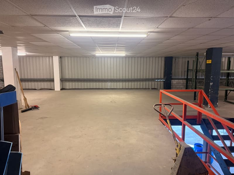 Empty room with metal walls, concrete floor, metal railings, and a broom