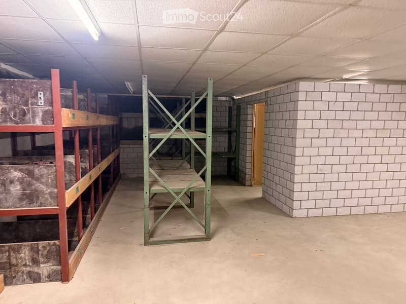Empty room with white ceiling, white brick wall, green metal shelves, and a wooden door.