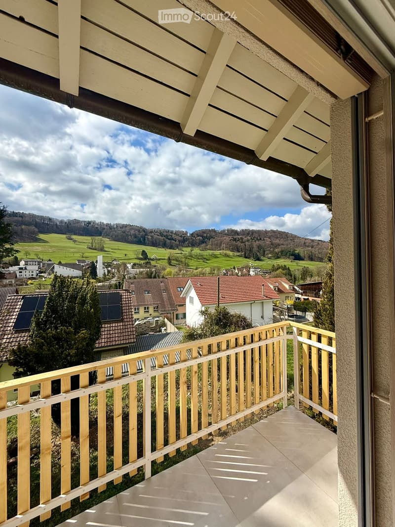 balcony with wooden railing, tiled floor, view of the village and mountains