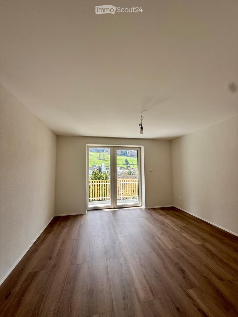 empty room, wooden floor, white walls, sliding glass doors to balcony, power outlet