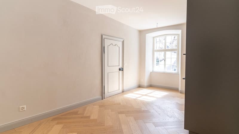 empty room, wooden floor, white walls, white door, window, power outlet