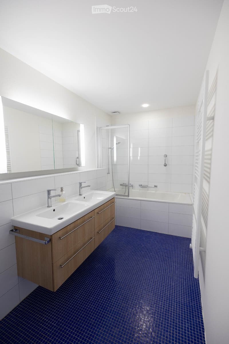 modern bathroom with blue tiles, white walls, two sinks, large mirror, bathtub, shower