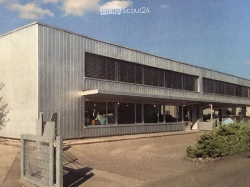 modern industrial building, metal walls, large windows, gated entrance, concrete driveway