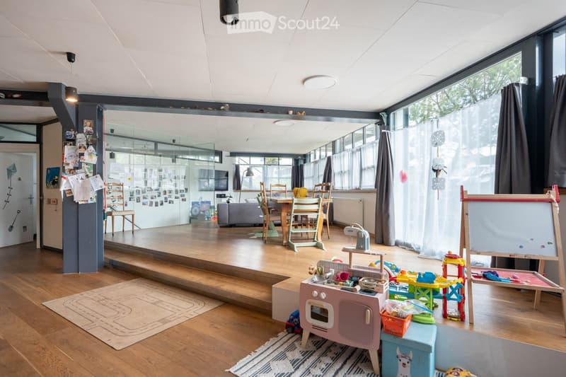 large room, wooden floor, large windows, dining table, chairs, toys, play area, radiator