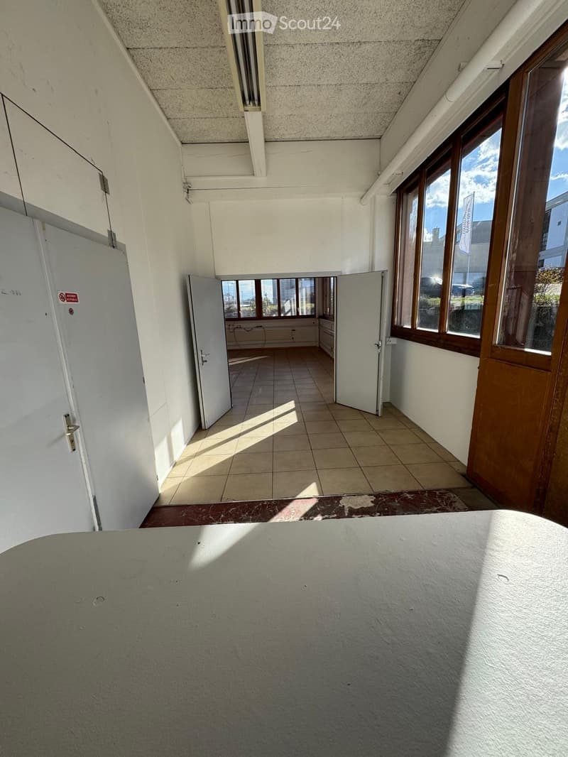 Empty room with white walls, tiled floor, two open doors, and large windows