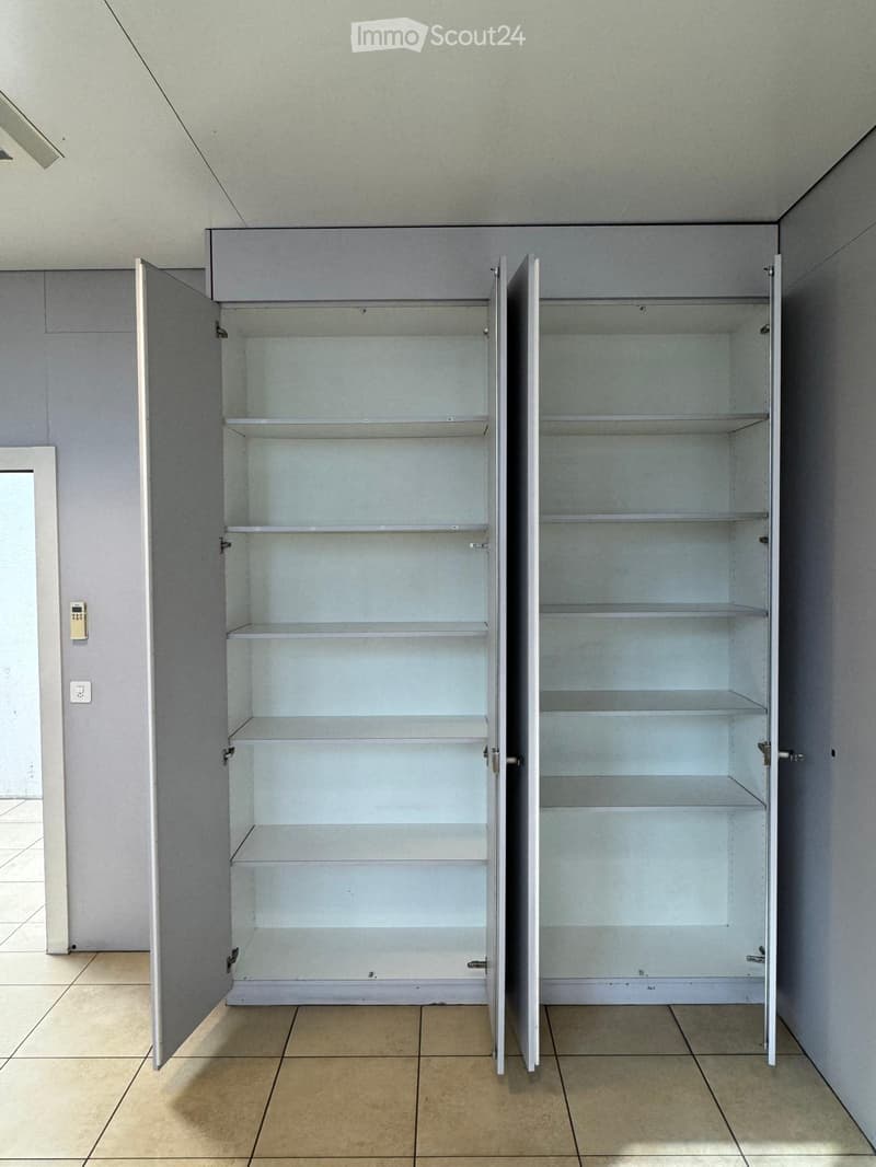 Two open wardrobes with multiple shelves, empty, gray walls, tiled floor