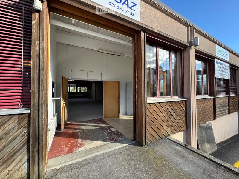 Commercial building with wooden exterior, open entrance, tiled floor, glass windows, red shutters, sign reading 'GAZ', and a sign for 'SOPROSHOP'.