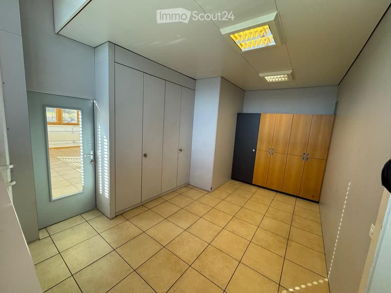 Empty room with tiled floor, white walls, built-in cabinets, and a door.