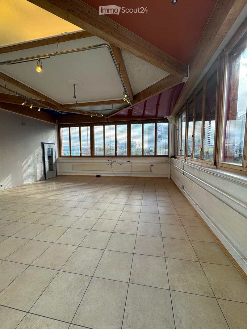 large room, white walls, wooden beams, tiled floor, large windows, view of the city