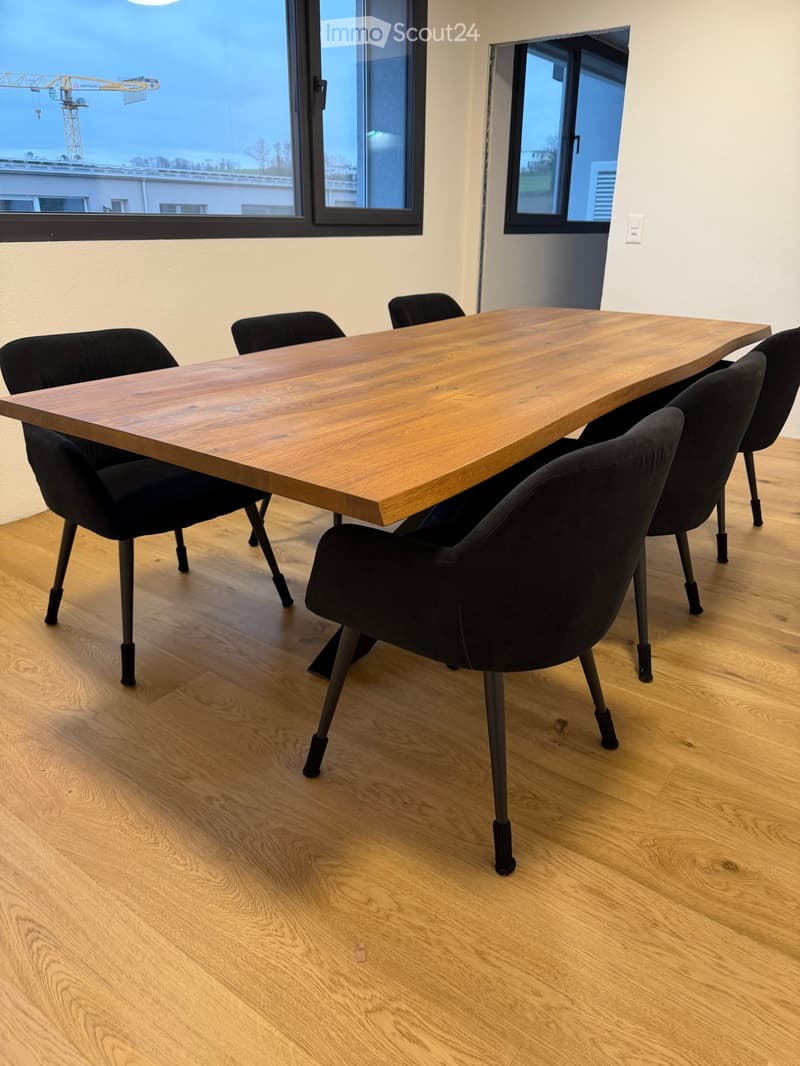 large wooden table, black chairs, wooden floor, large windows