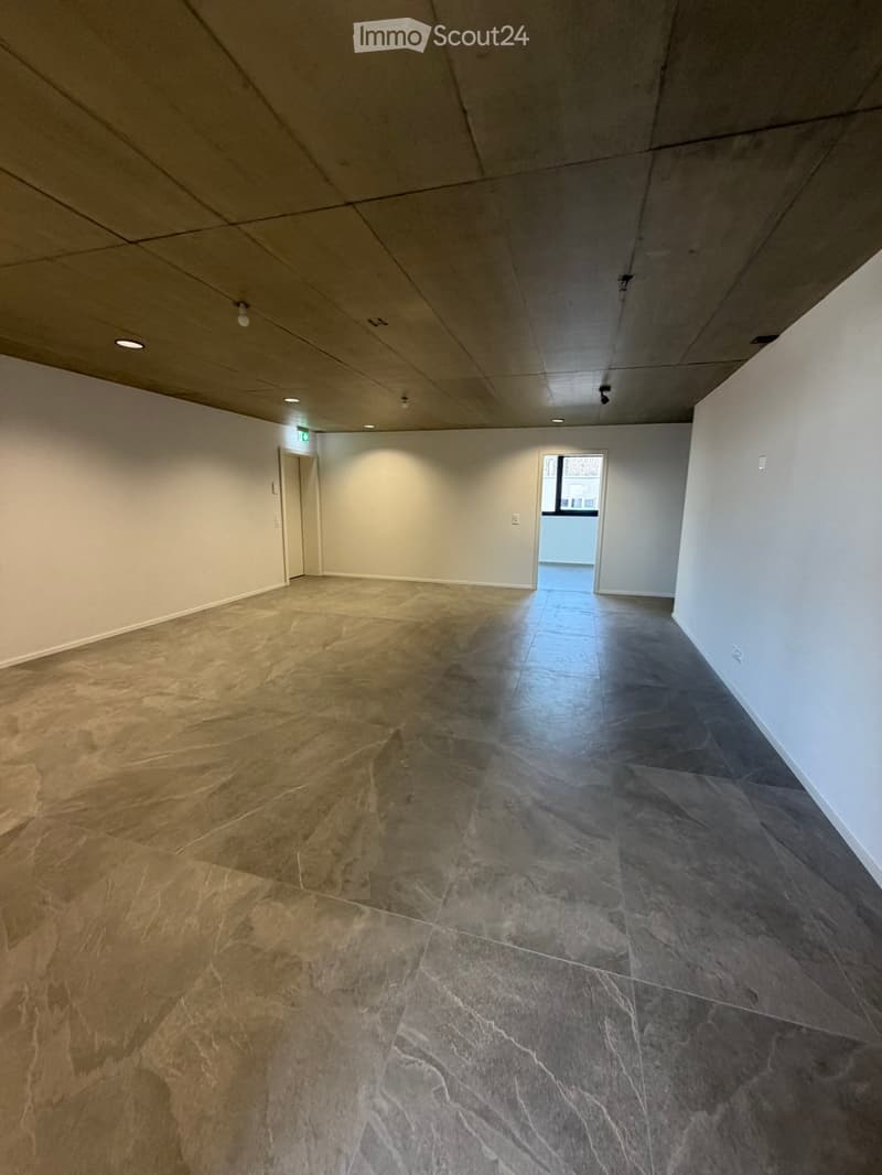 Empty room with gray tiled floor, white walls, two doors, and ceiling lights