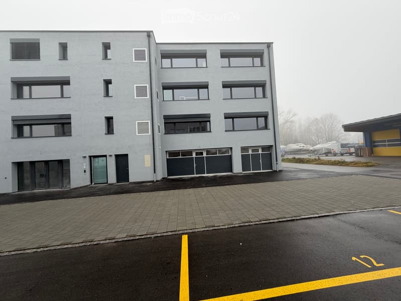 4 story building, grey exterior, multiple windows, garage, parking lot