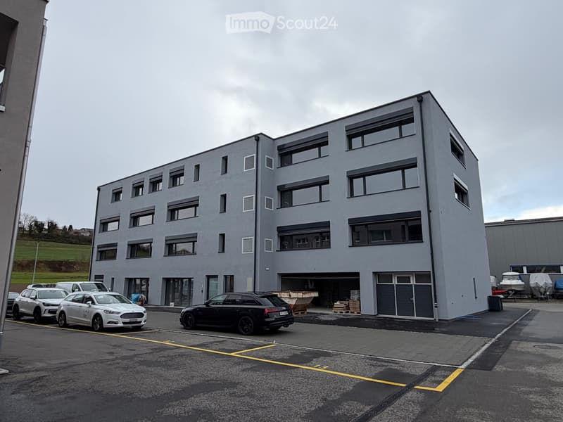 4 story building, grey exterior, multiple windows, cars parked in front