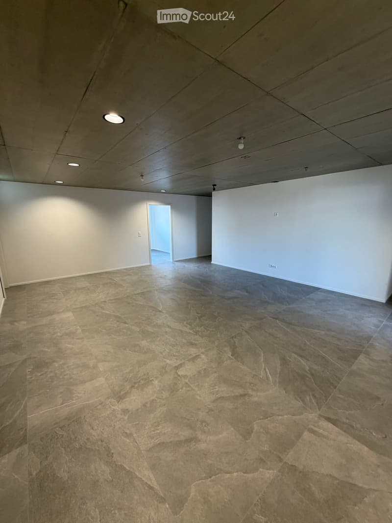 Empty room with white walls, gray tiled floor, and ceiling lights