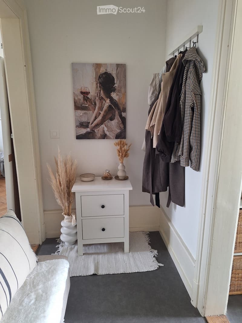 white walls, white floor, white nightstand, white rug, white couch, painting, coat rack, decorative items
