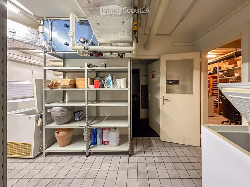 Storage room with shelves, boxes, and various items, open door, tiled floor, ventilation system