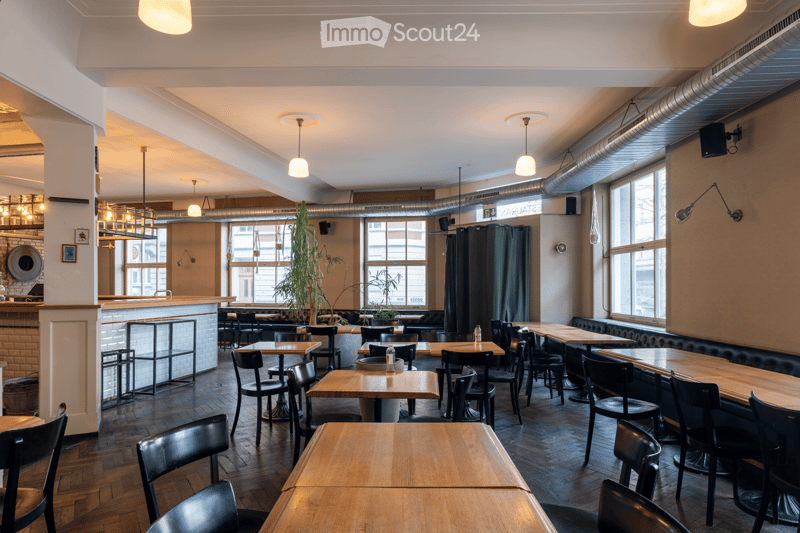 wooden tables, black chairs, white walls, large windows, wooden floor, bar counter, plants