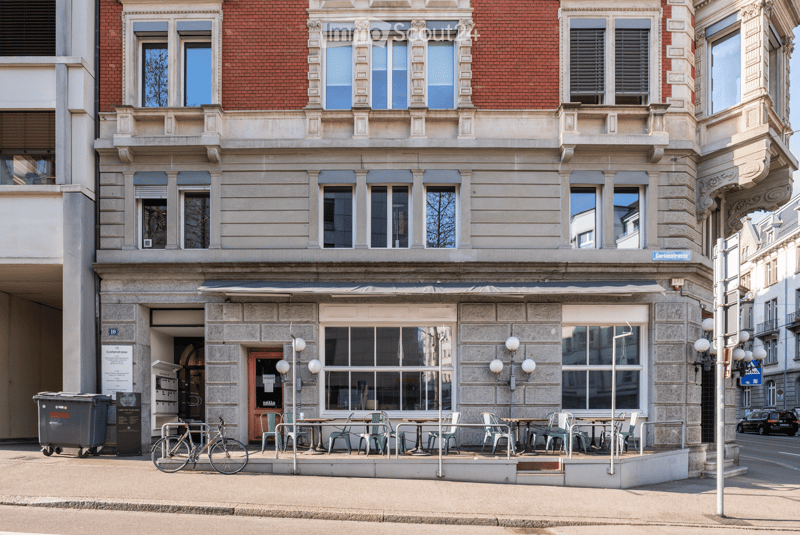 3 story building, brick facade, large windows, outdoor seating area, bicycle parked