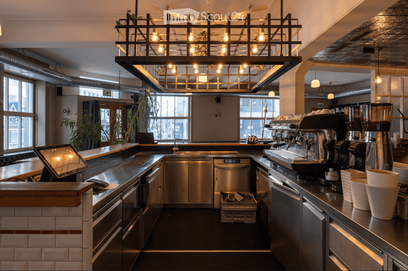 modern kitchen with stainless steel appliances, large windows, hanging lamps, countertop, monitor, coffee machine, plates, cups