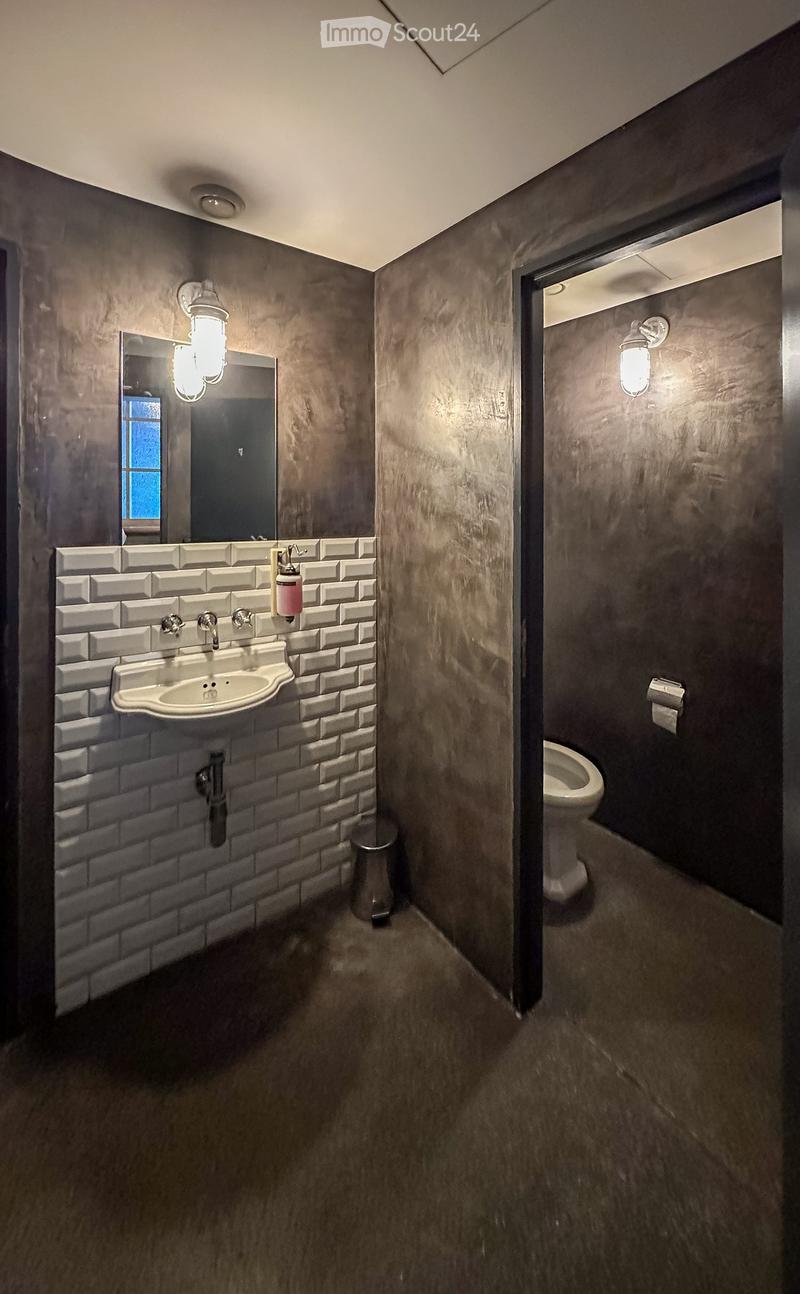 Bathroom with white sink, mirror, toilet, and gray walls