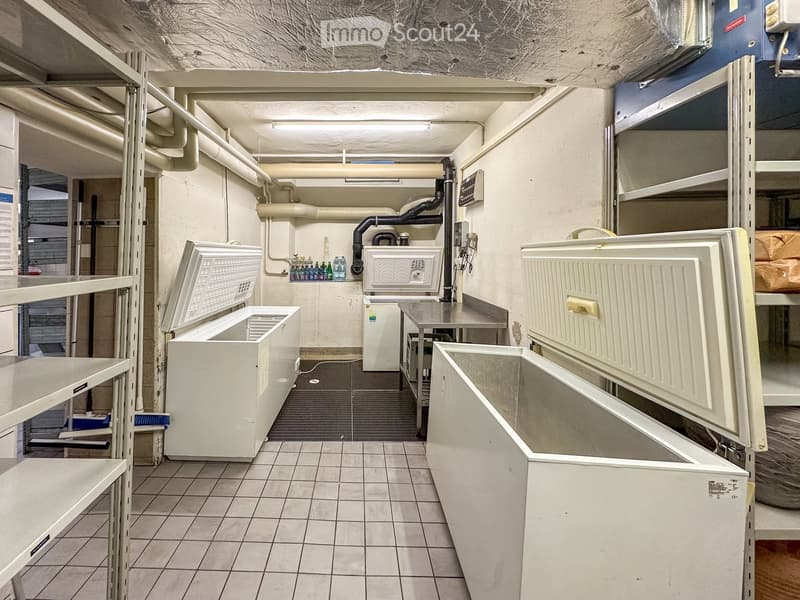 Storage room with white freezers, shelves, tiled floor, metal table, and various equipment