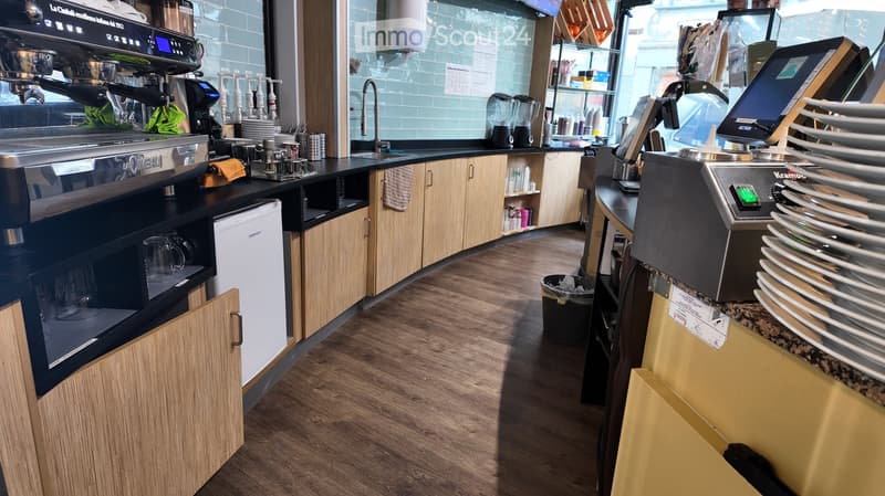 wooden countertops, wooden cabinets, stainless steel appliances, tiled walls, black sink, stainless steel coffee machine, black trash bin, monitors, plates