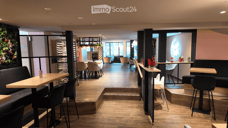 Open space restaurant with wooden floors, black high chairs, wooden tables, black benches, white chairs, multiple hanging plants, a decorative fireplace