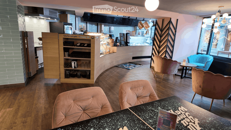Coffee shop interior with a counter, wooden shelves, armchairs, tables, green tiled wall, wooden flooring, chandelier