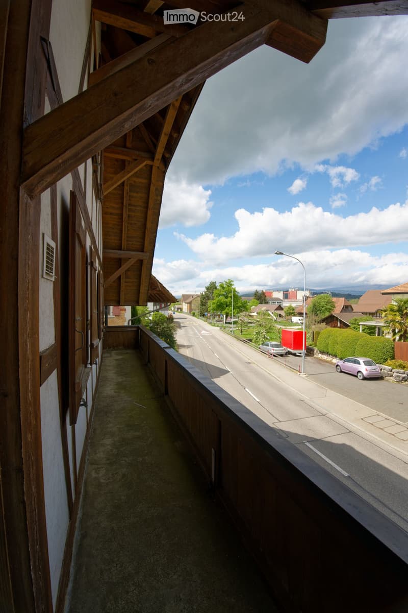 balcony with wooden railing, street view, parked cars, street light, houses, trees