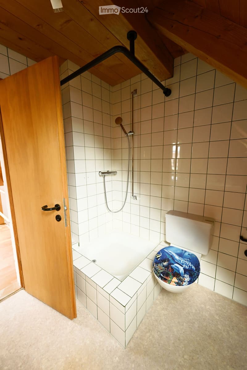 Bathroom with wooden door, white tiles, shower, toilet, and a small bathtub