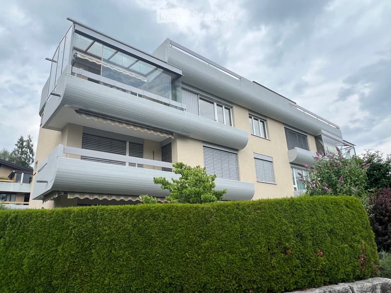 3 story house, beige exterior, multiple balconies, glass railings, hedges