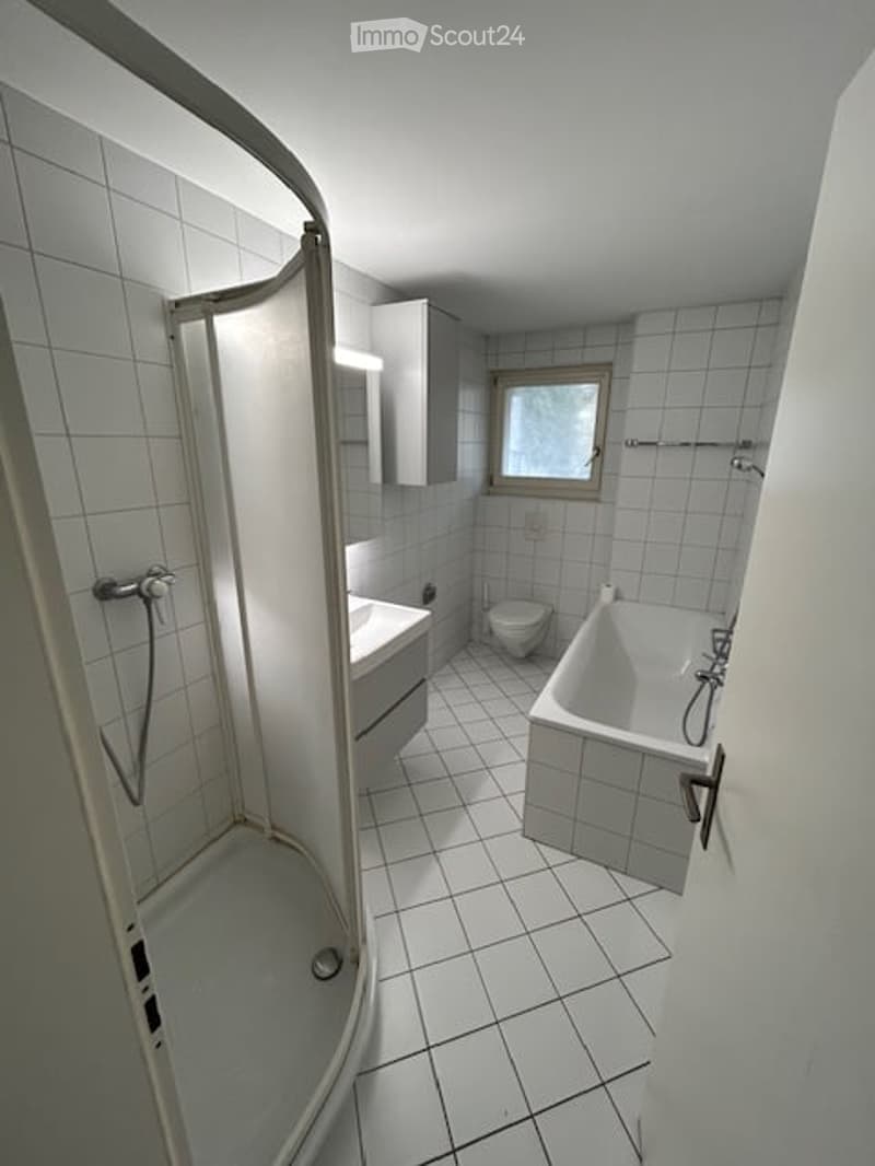Bathroom with white tiles, bathtub, shower, toilet, sink, and cabinet