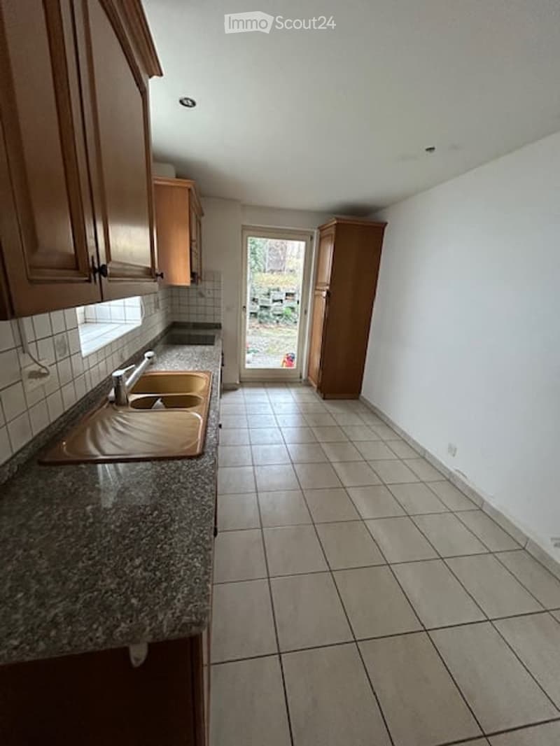 Empty kitchen with wooden cabinets, granite countertop, double sink, and tiled floor.