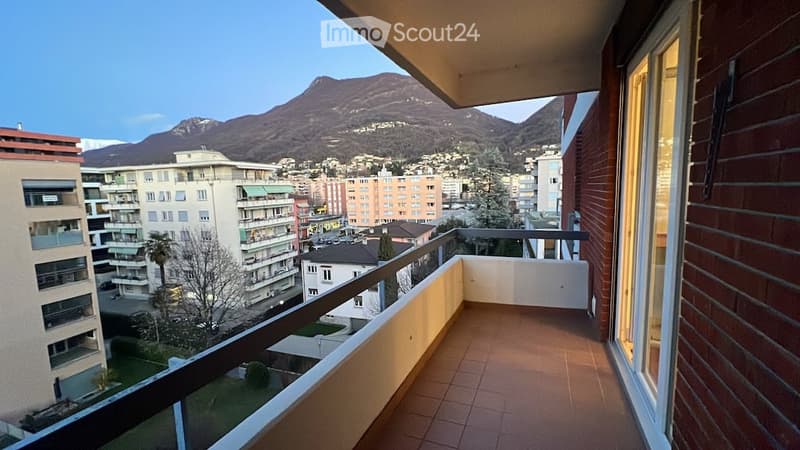 Balcony with tiled floor, metal railing, glass door, view of mountains and city