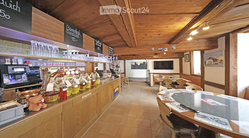 wooden counter, wooden chairs, wooden tables, blackboards, bottles, coffee machine, TV