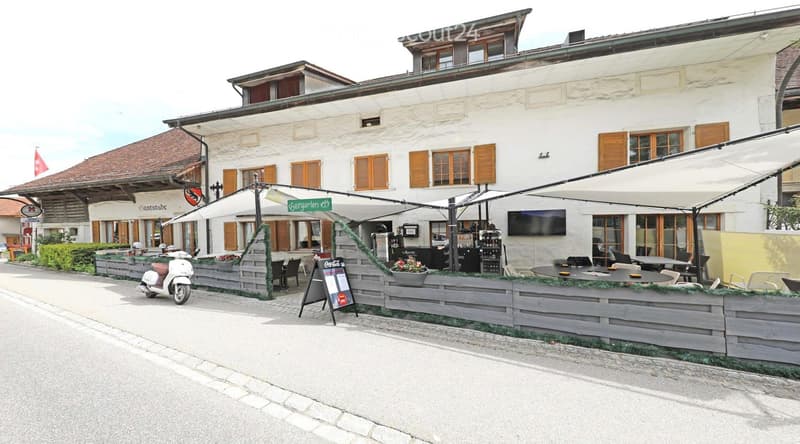 white building, wooden shutters, awnings, outdoor seating, tables, chairs, plants, scooter, flag