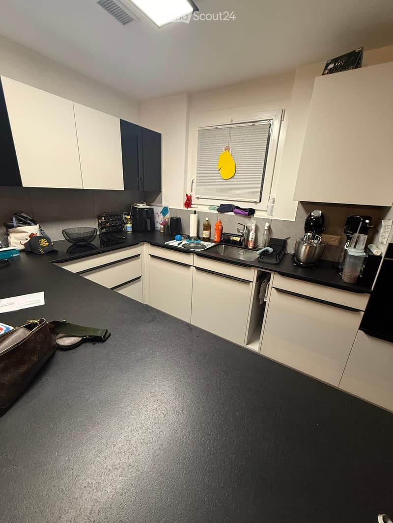 modern kitchen with black countertops, white cabinets, black and white tiled backsplash, sink, appliances, and a window