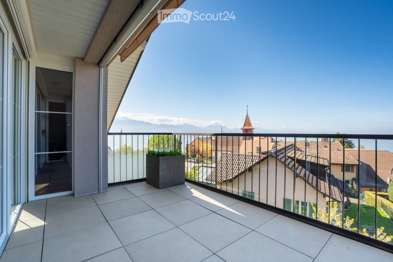 Balcony with tiled floor, black railing, potted plant, glass doors, view of houses and mountains