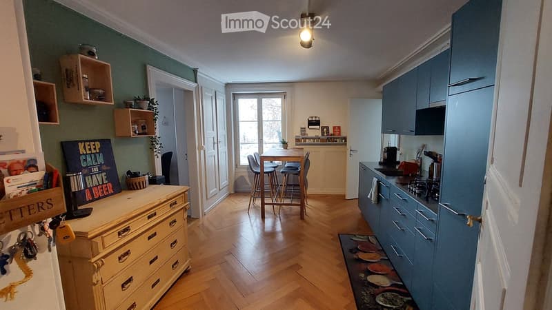 kitchen with wooden floor, wooden table, chairs, blue cabinets, wooden dresser, green wall, shelves, potted plants, light fixture