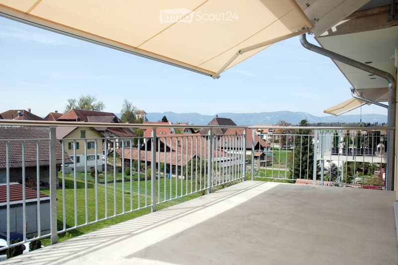 Balcony with metal railings, retractable awning, view of the town and mountains