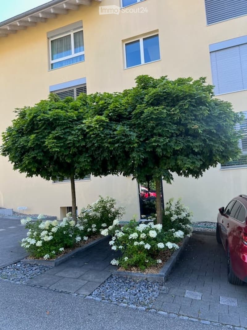 Building with beige walls, two windows, and a red car parked in front