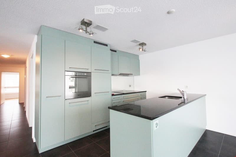 modern kitchen with white and blue cabinets, black countertops, stainless steel appliances, and tiled flooring
