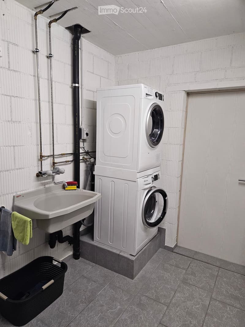 Laundry room with washing machine, dryer, sink, and storage basket